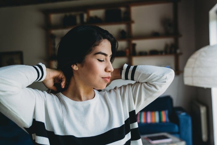 young woman looking out window in apartment