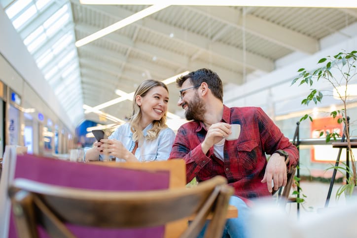 Young couple in shopping center using phone