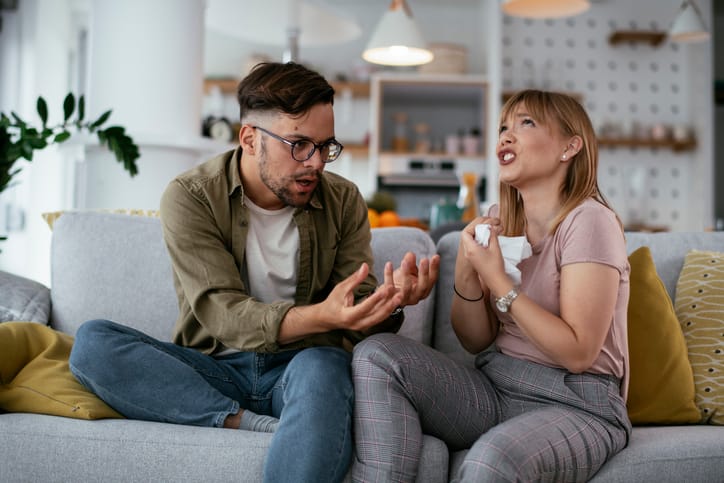 Boyfriend and girlfriend are arguing on the couch. Angry woman is yelling at her boyfriend.