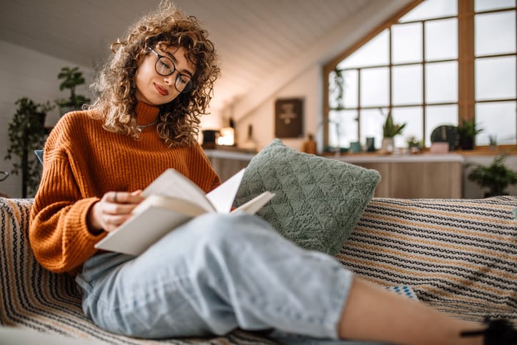 woman reading book on couch