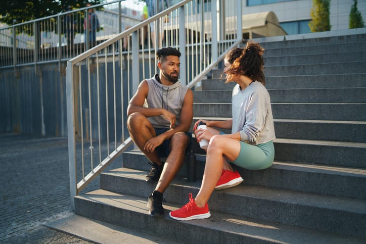 male female runner sitting on steps afer exercise