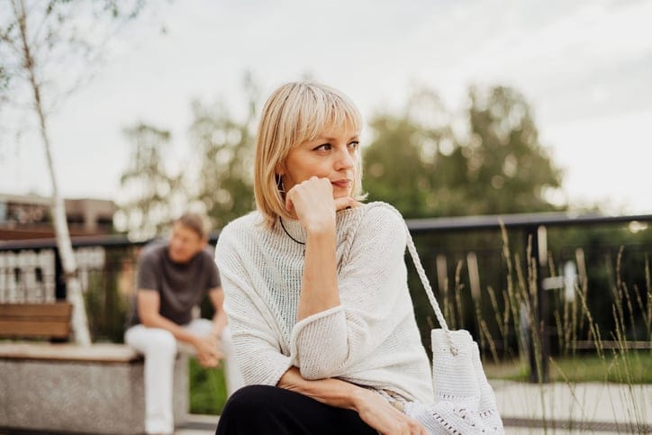 sad woman at playground with man behind her