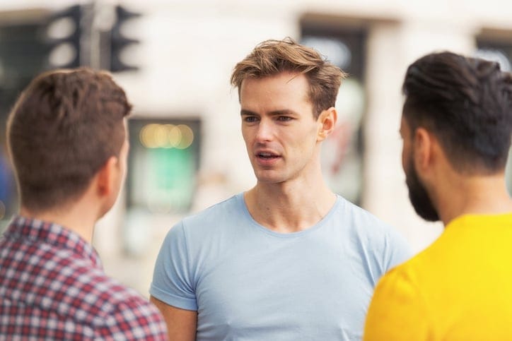 three men talking outside