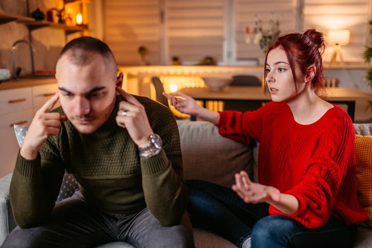 A young couple with relationship problems arguing on the sofa in the living room.