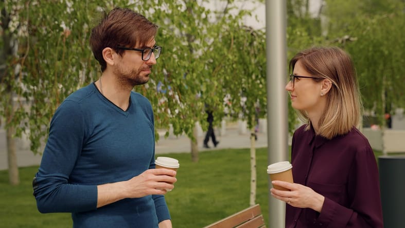 man and woman with coffee talking outside