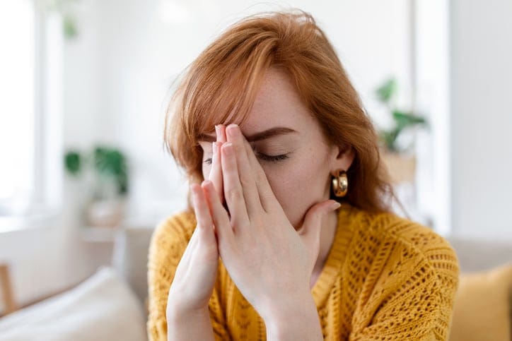 Woman covering her face with hands.