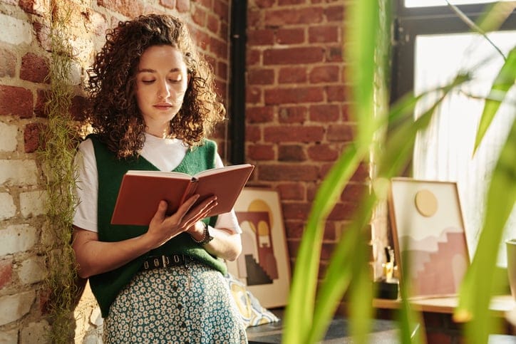 woman leaning against wall reading