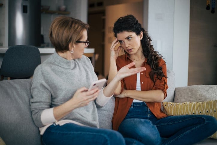 Young woman with head in hands talking to her mother.