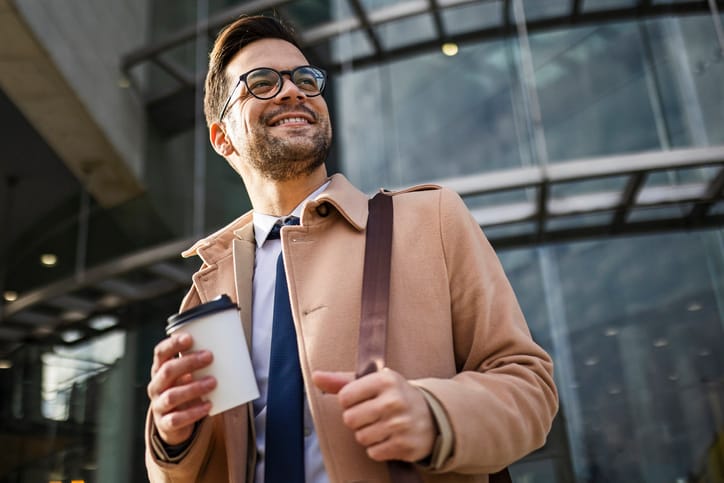 Handsome young businessman walking drinking coffee
