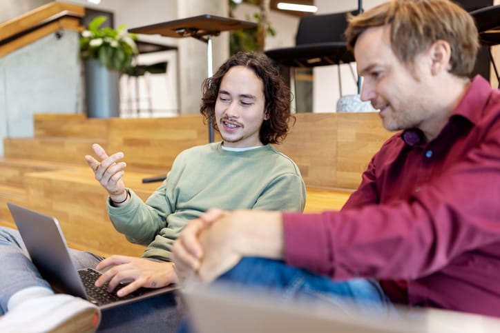 two male colleauges studying something on laptop