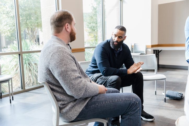 two men talking in group setting