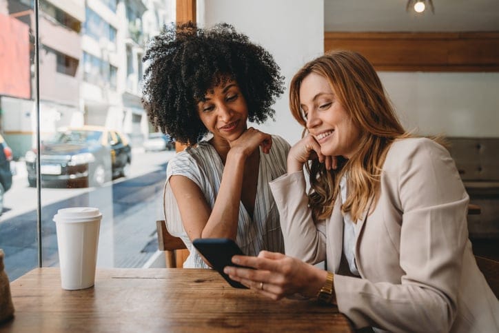 Two women looking at tablet in cafe.