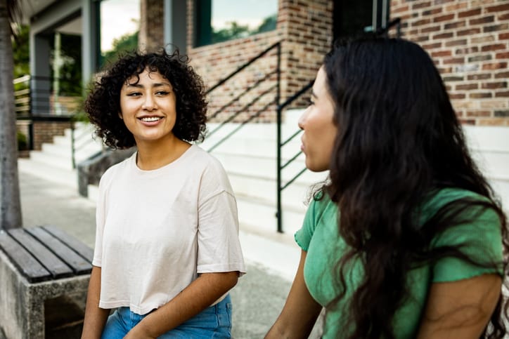conversation Two young women sitting outdoors and talking