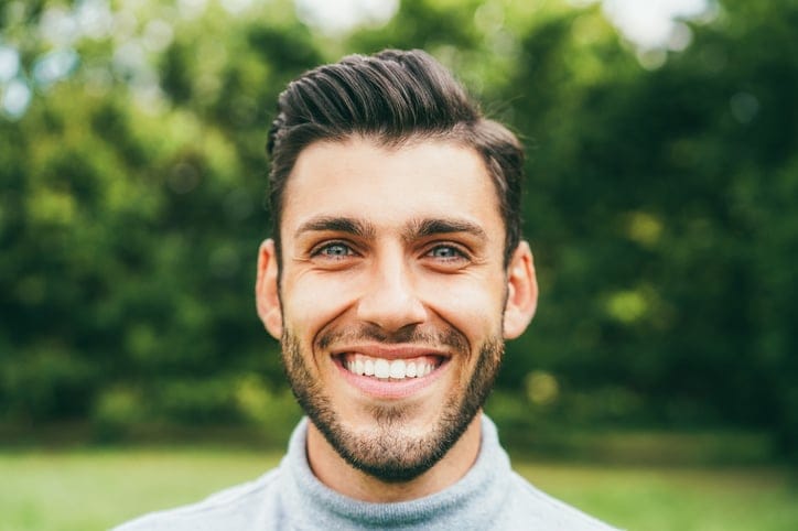 Smiling man with striking eyes in park.
