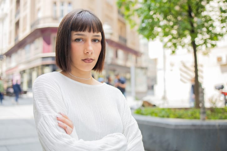 stern millennial woman arms crossed outside