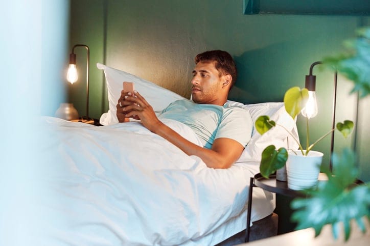 Relax, search and phone with man in bedroom for social media, streaming and communication. Text message, network and internet with male browsing in bed at home for contact, technology and reading