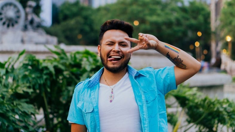 Handsome man smiling and grimacing looking at camera with LGBT community paint.