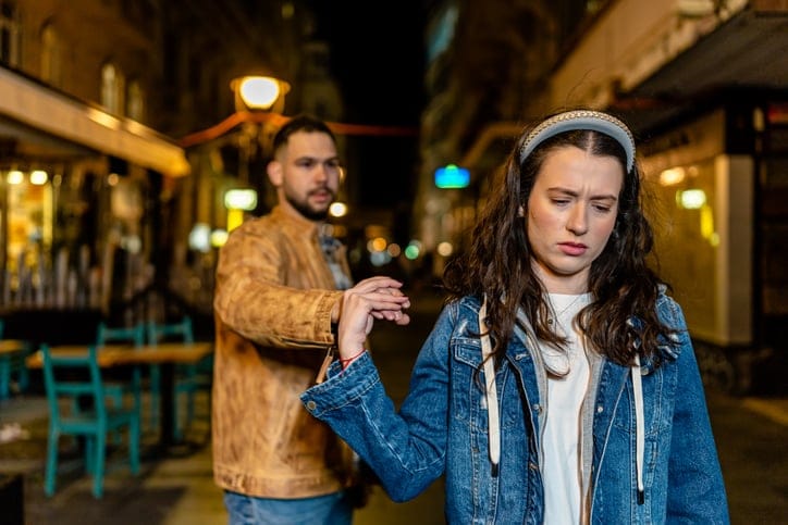 Young couple arguing on a crowded promenade.