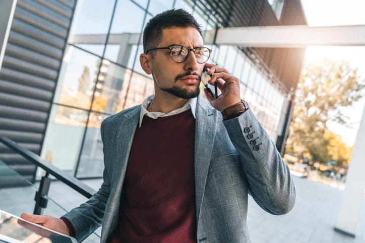 Young serious businessman talking on mobile phone in office.