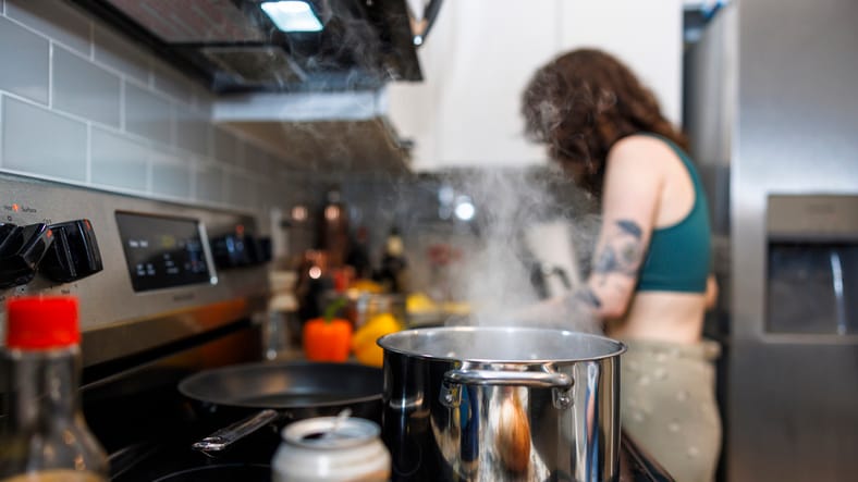Stainless boiling pot with steam on stove.