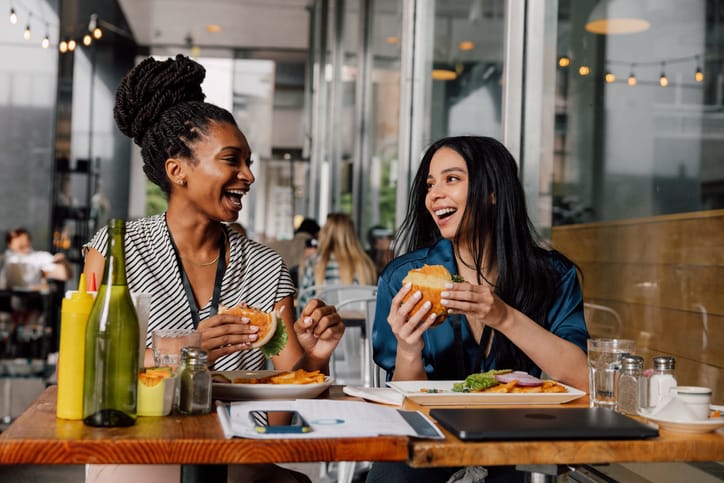 Two women eating hamburger.
