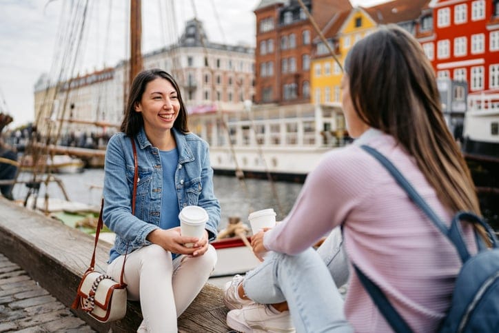 two female friends sitting by the water chatting