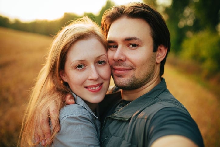 Portrait of young happy couple in a field.