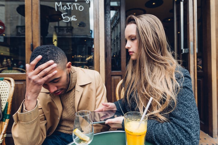 A concerned couple at an outdoor cafe.