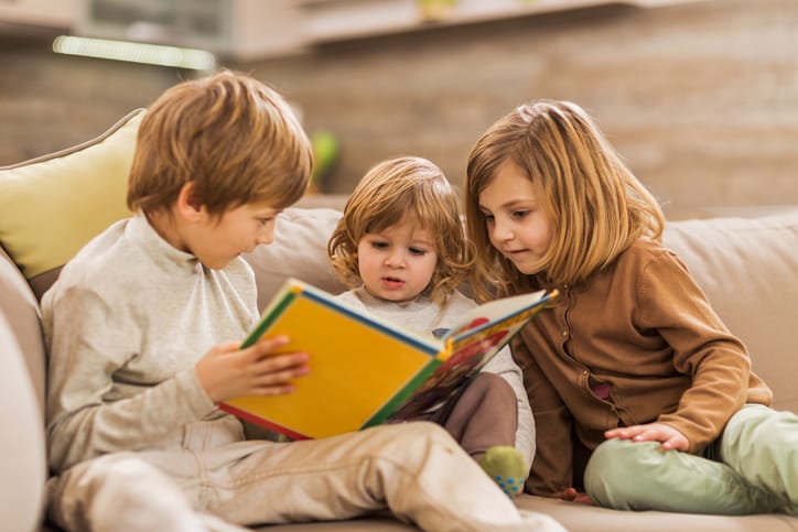 kids reading book on couch
