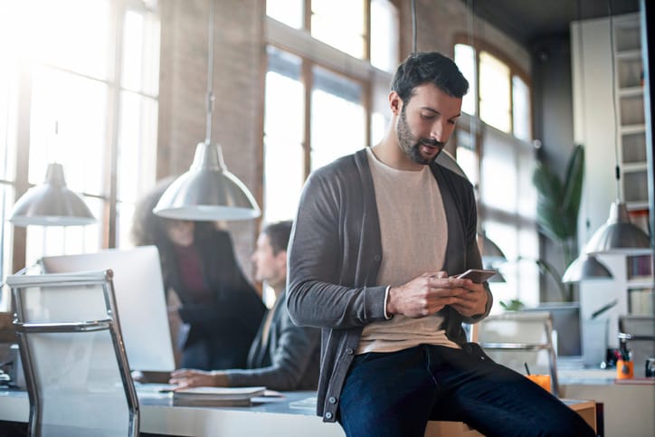 guy texting in office while working