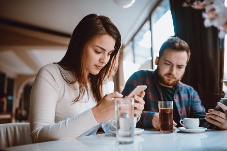 man and woman on their phones at restaurant