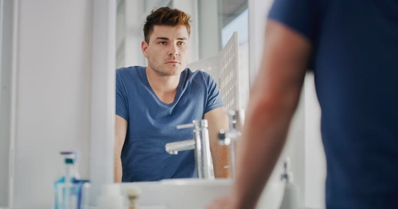 Young man looking in mirror with confidence.