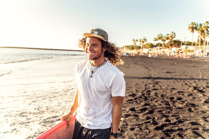 Man walking with surfboard on the beach.