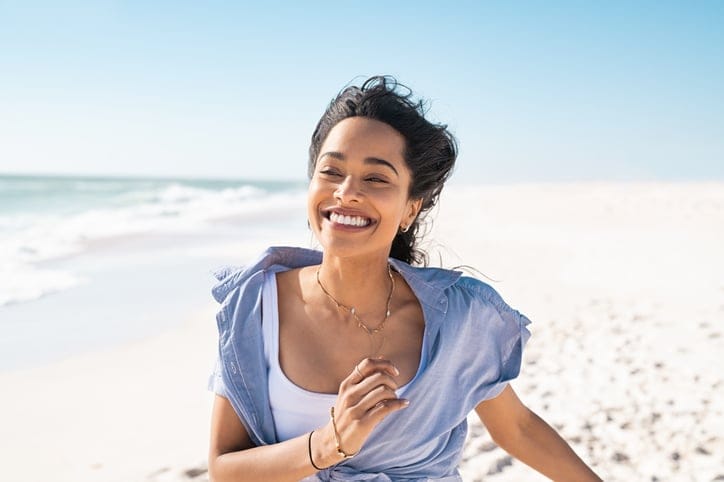 Happy smiling woman running on the beach.