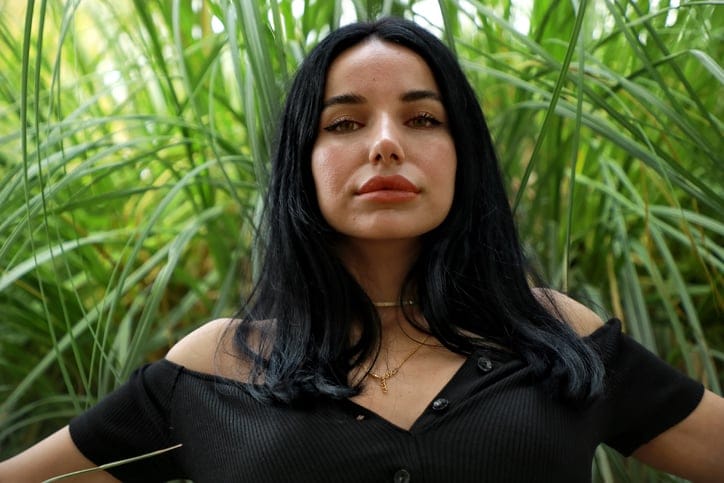Woman with black hair sitting on a park bench.