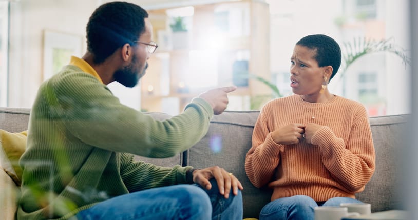 Frustrated man with his wife on the living room sofa.