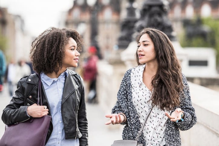 Two female friends talking outdoors.
