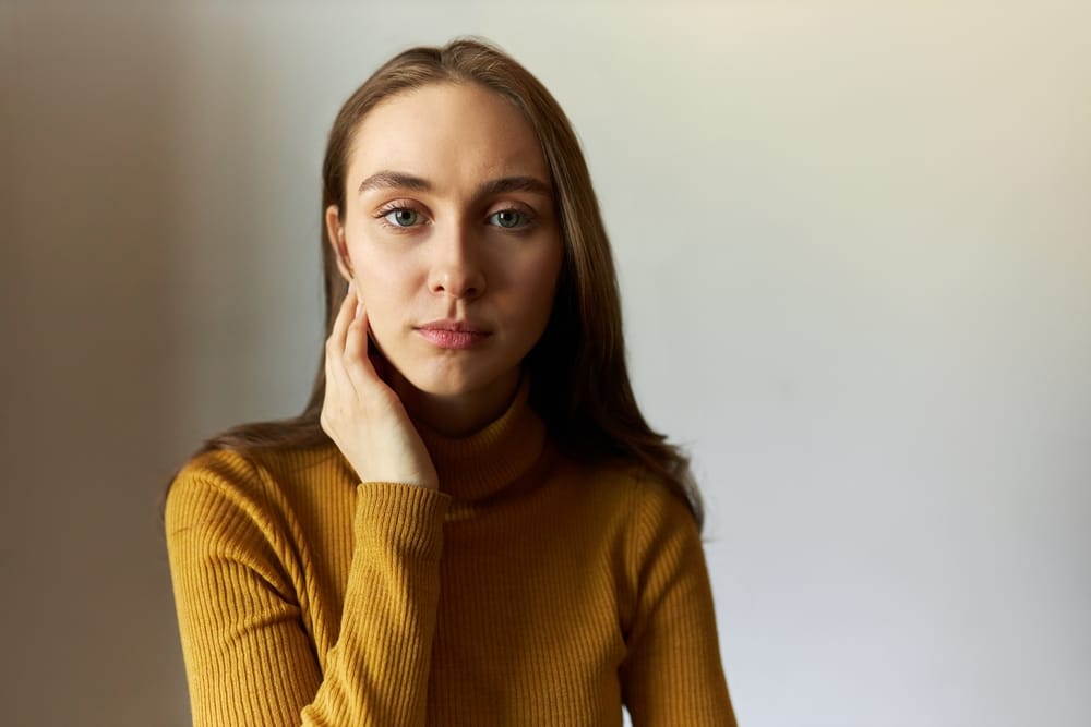 Young woman touching her neck.