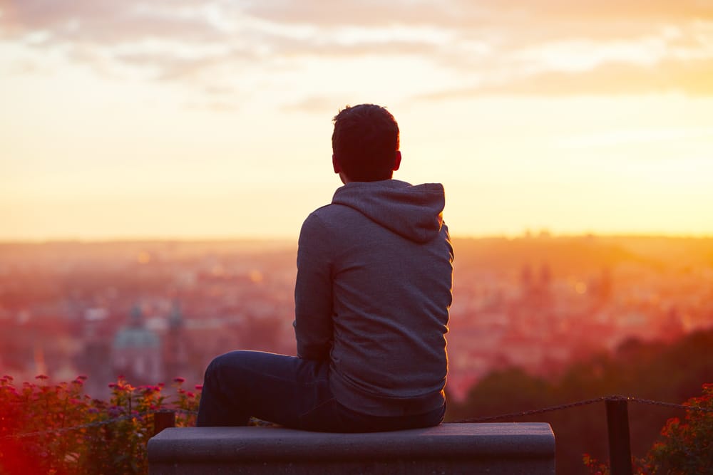 Young man looking out at sunset.