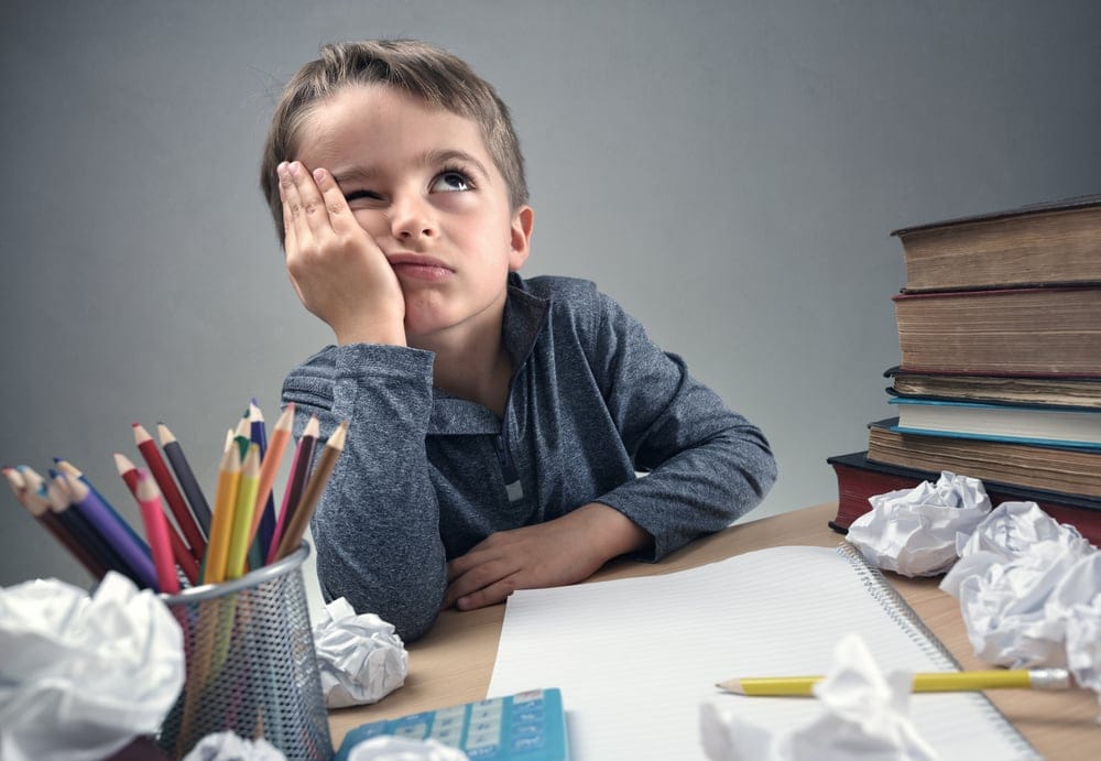 Small boy thinking with his head in his hand.