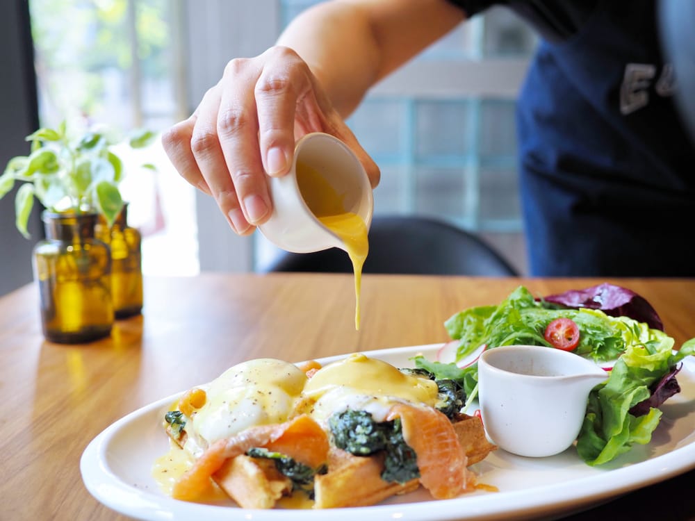 Woman pouring sauce over meal.