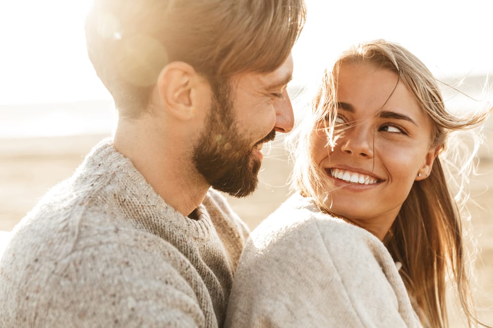 Smiling couple on sunny beach.