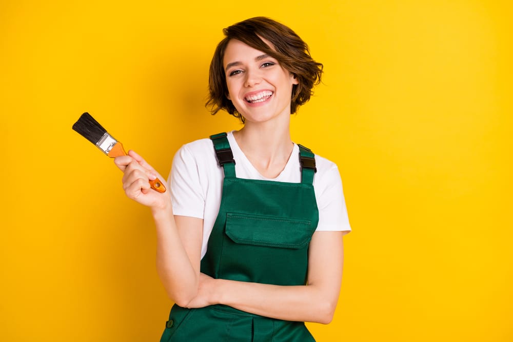 Woman smiling holding a paint brush.