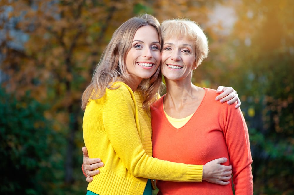 Mother and daughter standing together outside.