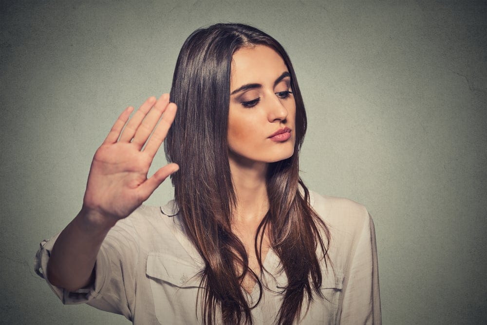 Woman with her hand up and eyes closed.