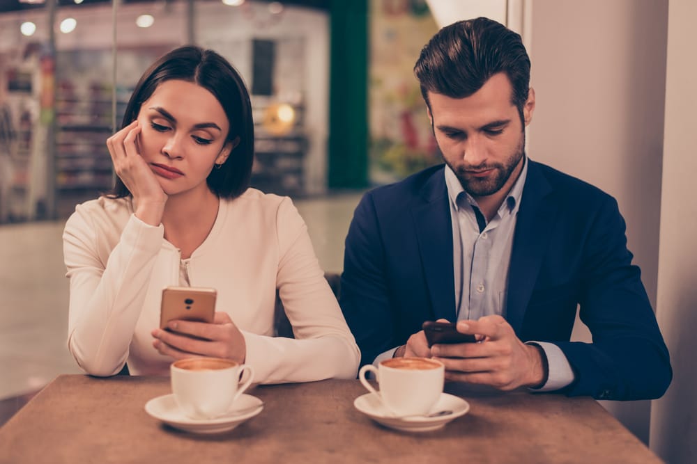 Couple in a cafe both on their phones.