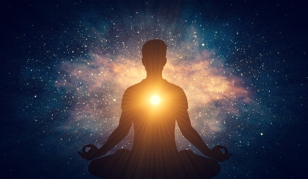 Man in front of the sun and stars doing yoga.