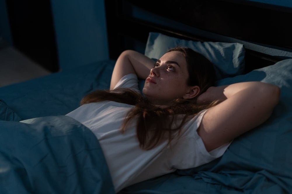 A woman laying awake in bed.