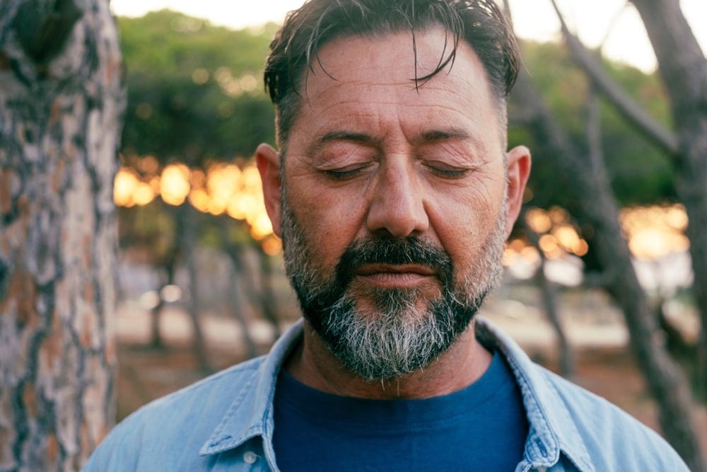 Man on a walk with his eyes closed.