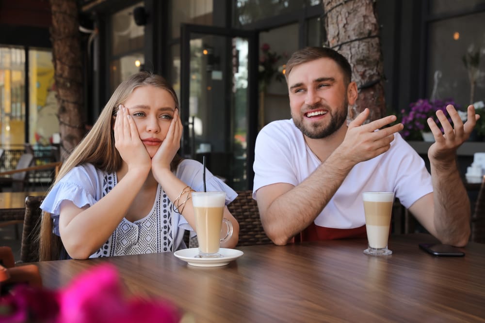 Young woman having boring date with talkative guy